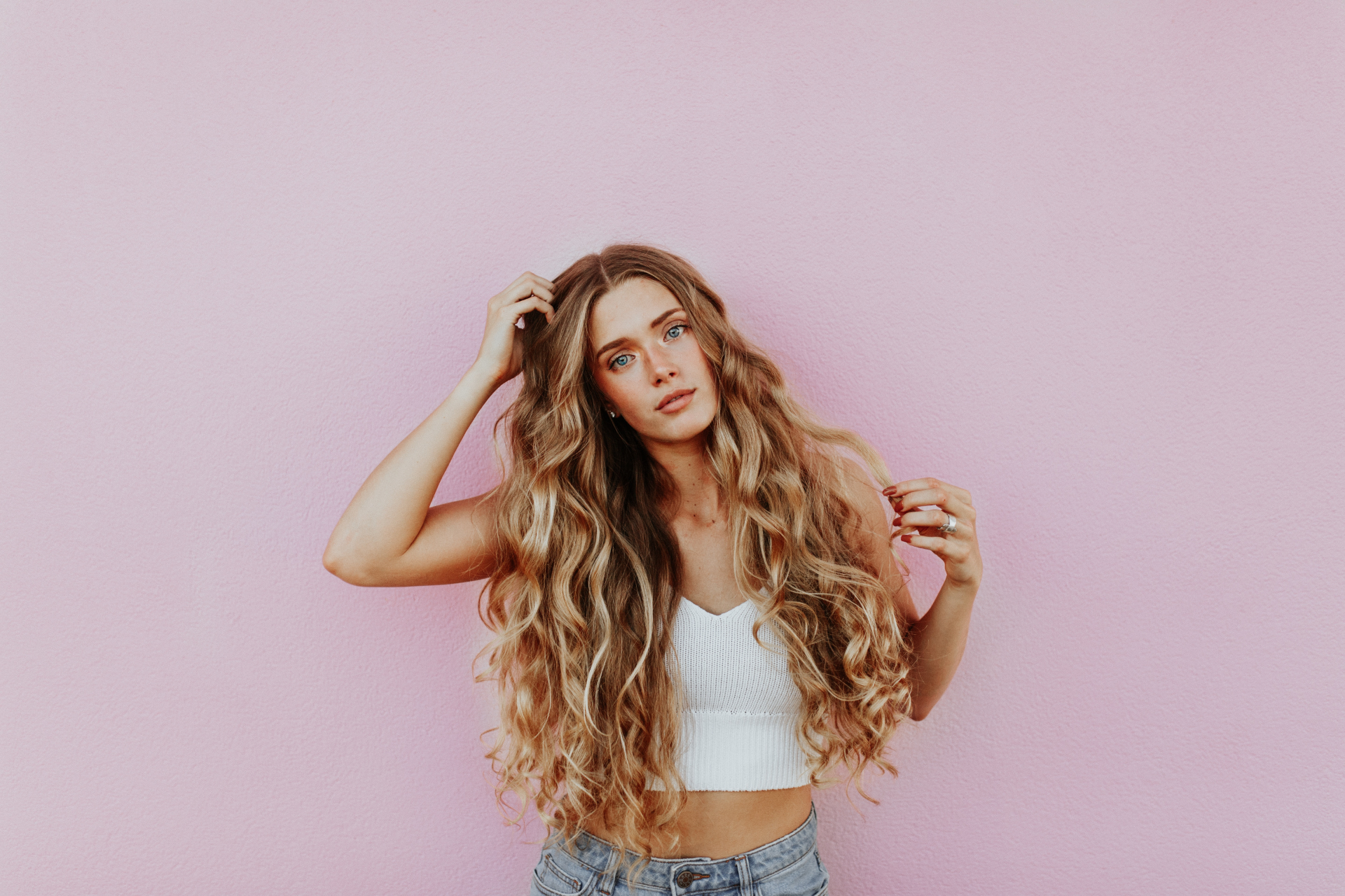 Long wavy hair against a pink wall